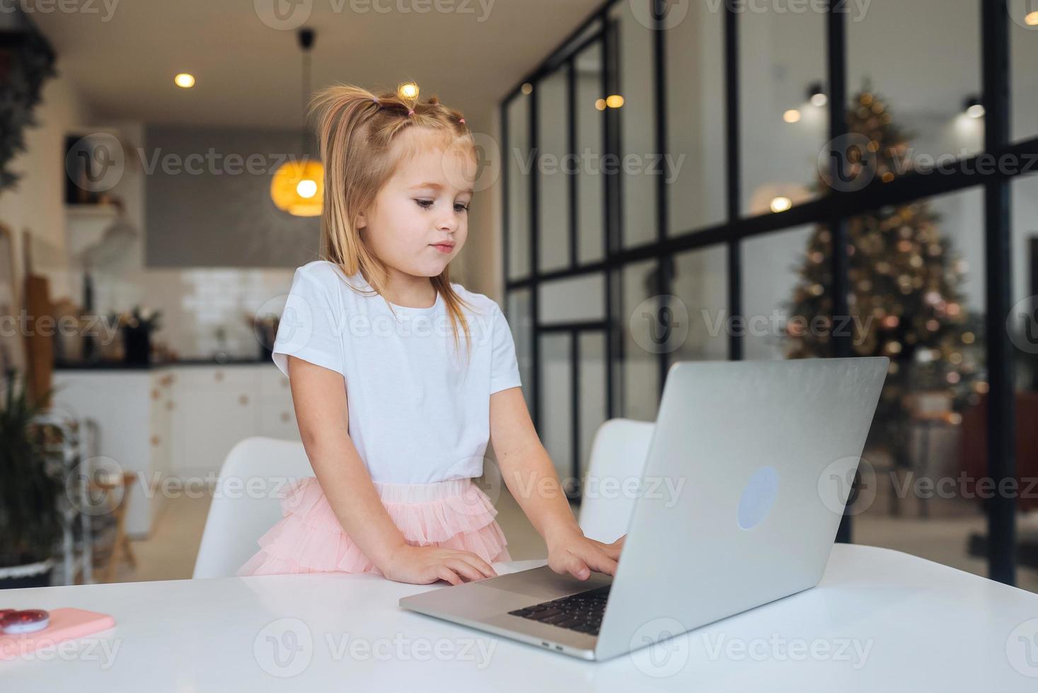 kleines Mädchen mit Tablet-Computer am Tisch sitzen foto