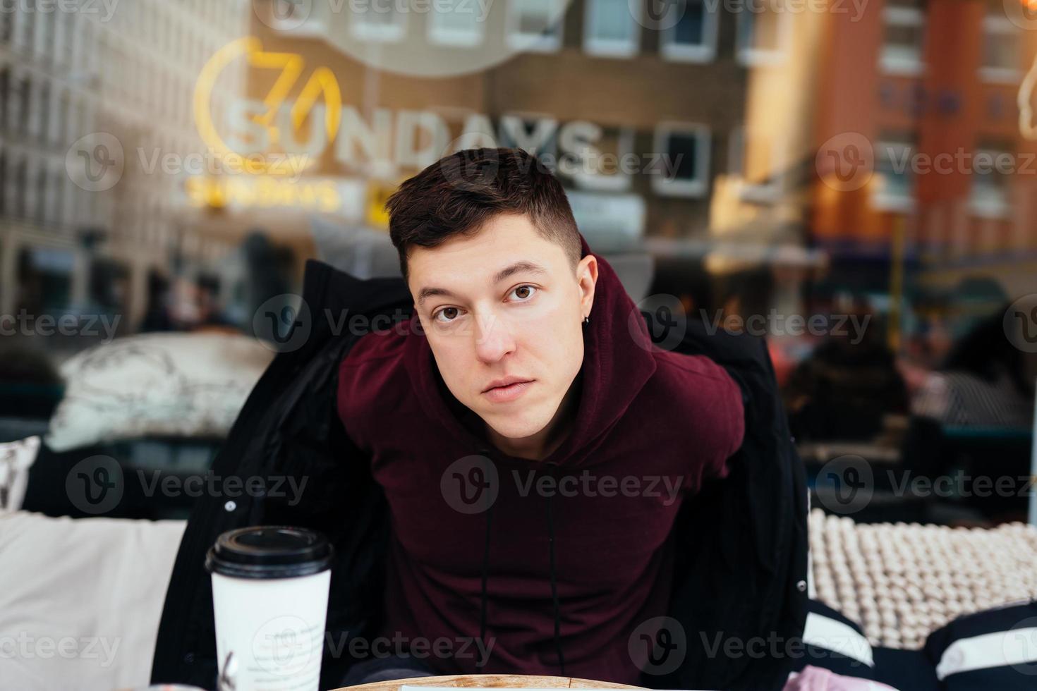 hübscher Kerl, der in einem Café im Freien rumhängt foto