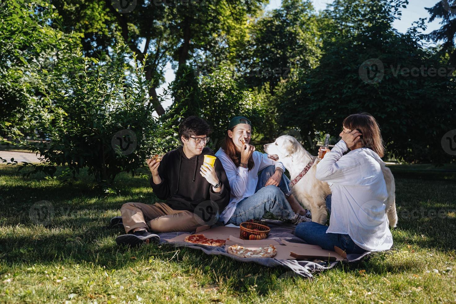 Gesellschaft von schönen jungen Leuten und Hunden, die ein Mittagessen im Freien haben. foto