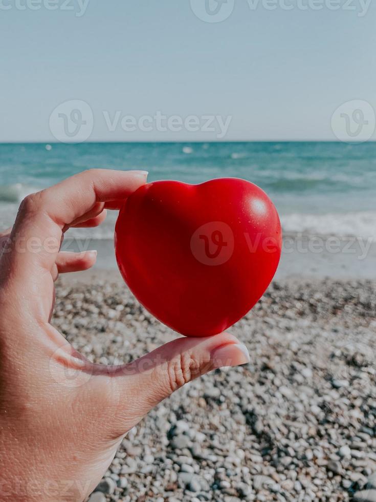 Eine Frau hält ein rotes Herz in der Hand foto