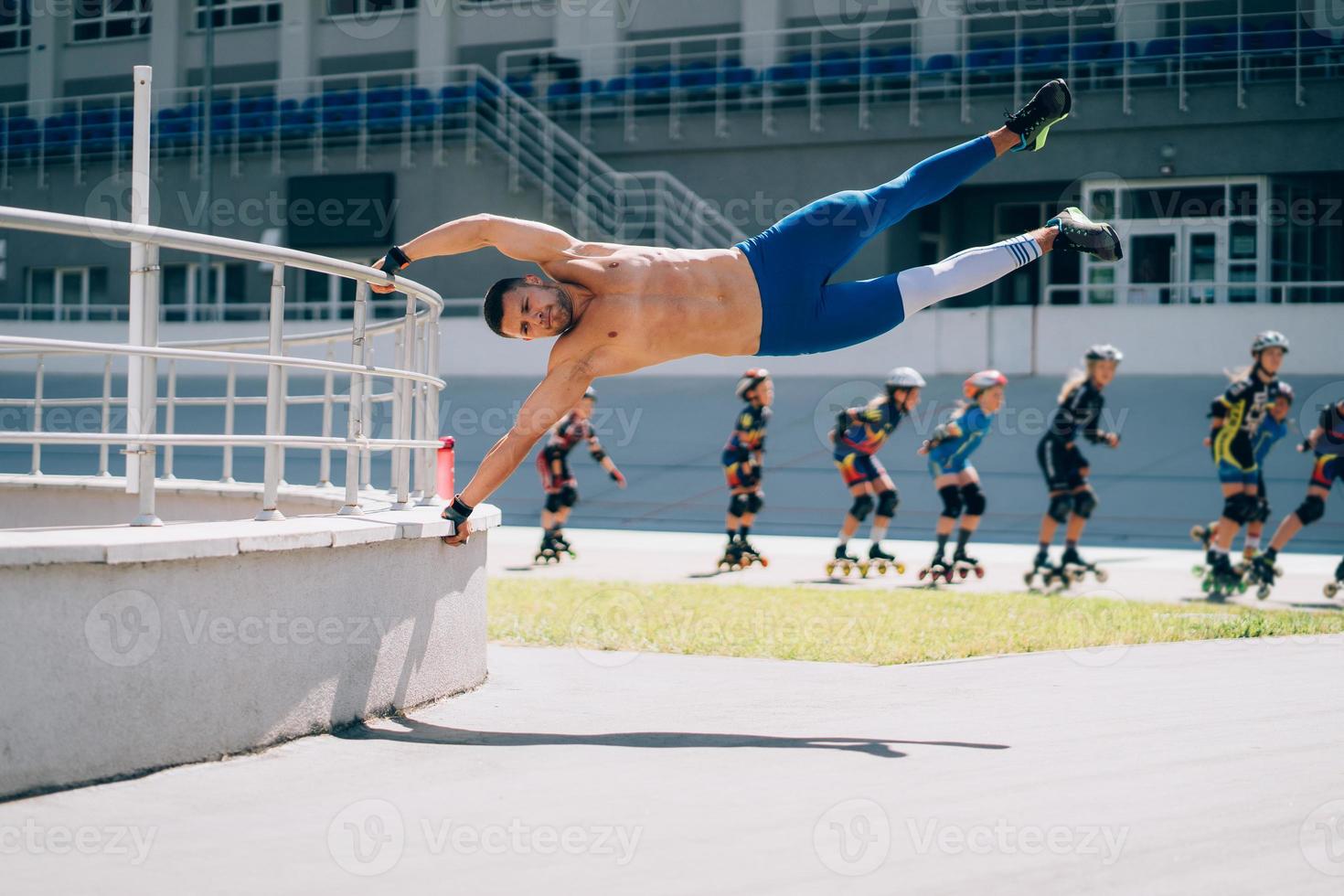 junger athletischer mann führt gymnastikelemente durch - menschliche flagge. foto