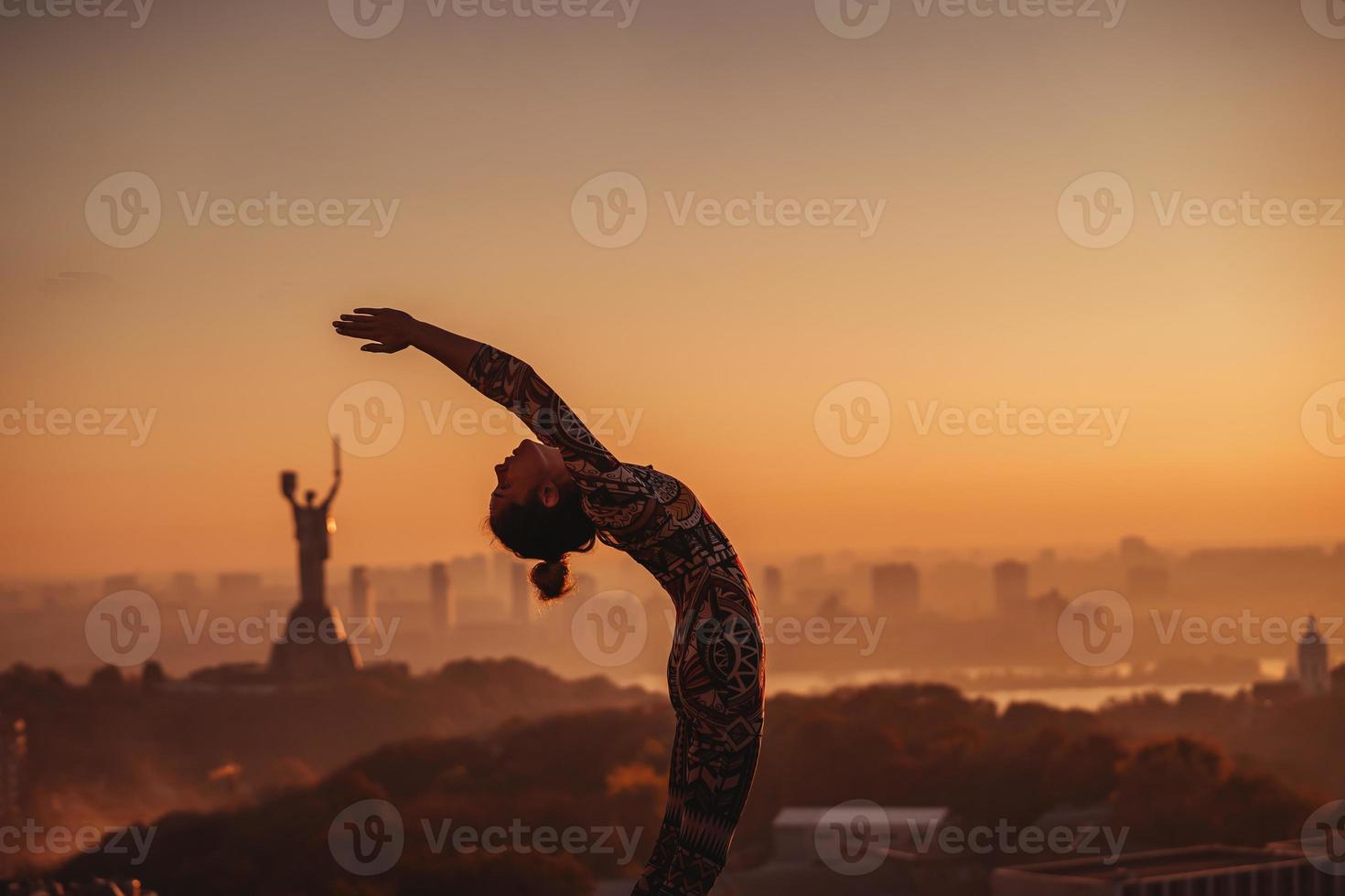 Frau beim Yoga auf dem Dach eines Wolkenkratzers in der Großstadt. foto