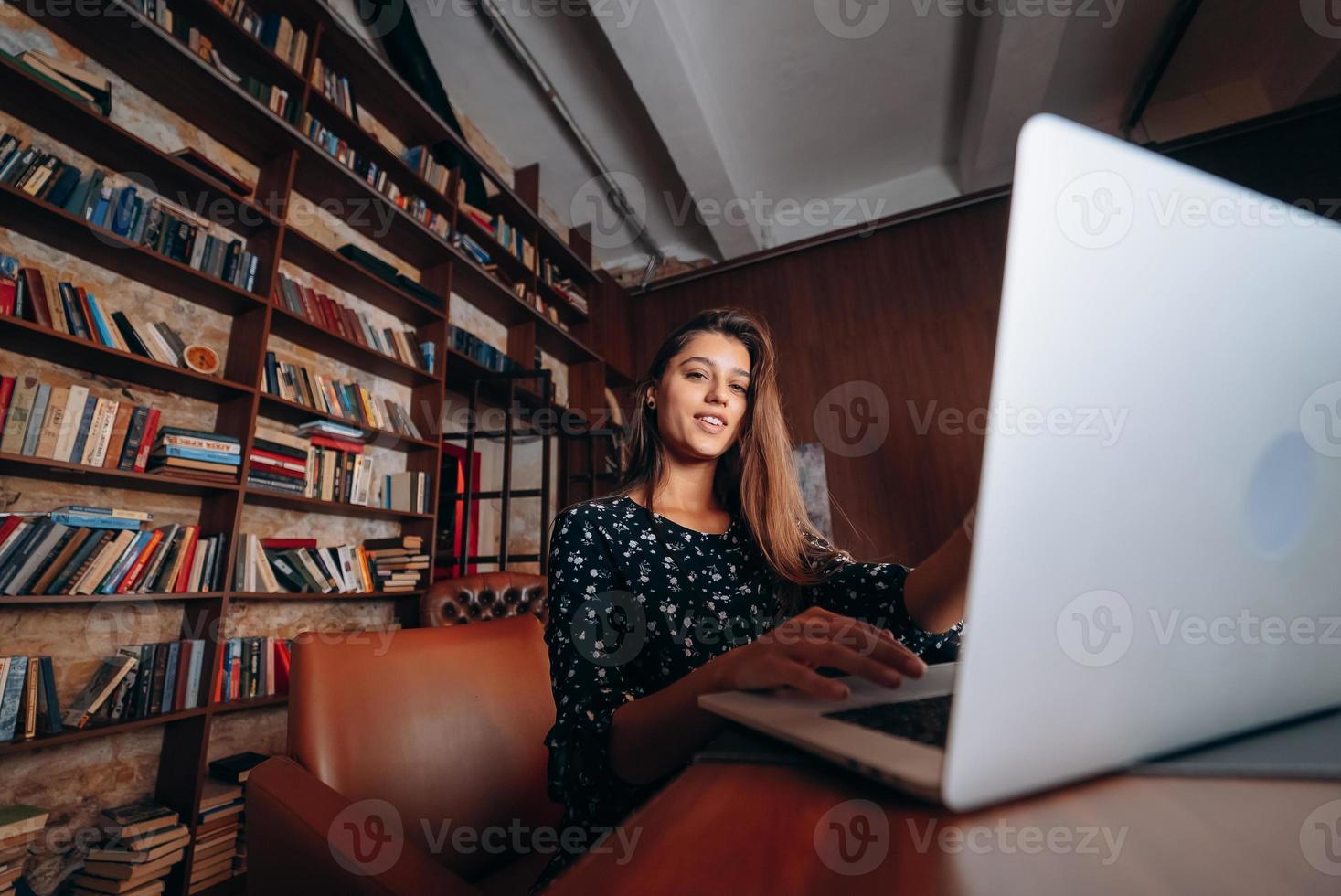 junge Frau mit Brille arbeitet am Laptop, während sie am Tisch sitzt foto