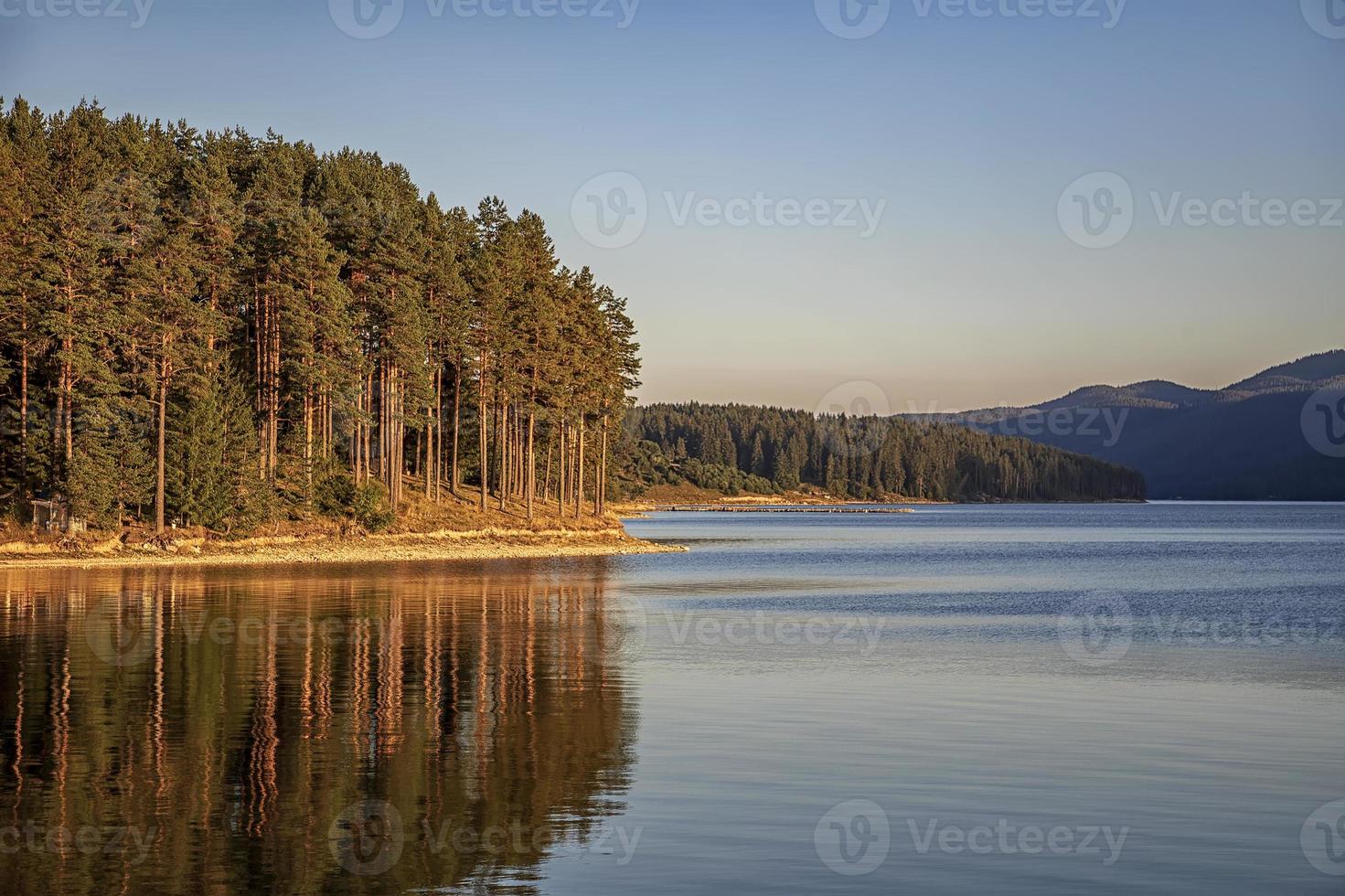 idyllische Berglandschaft am See mit ruhigem Wasser, Baumreflexion nach Sonnenuntergang foto