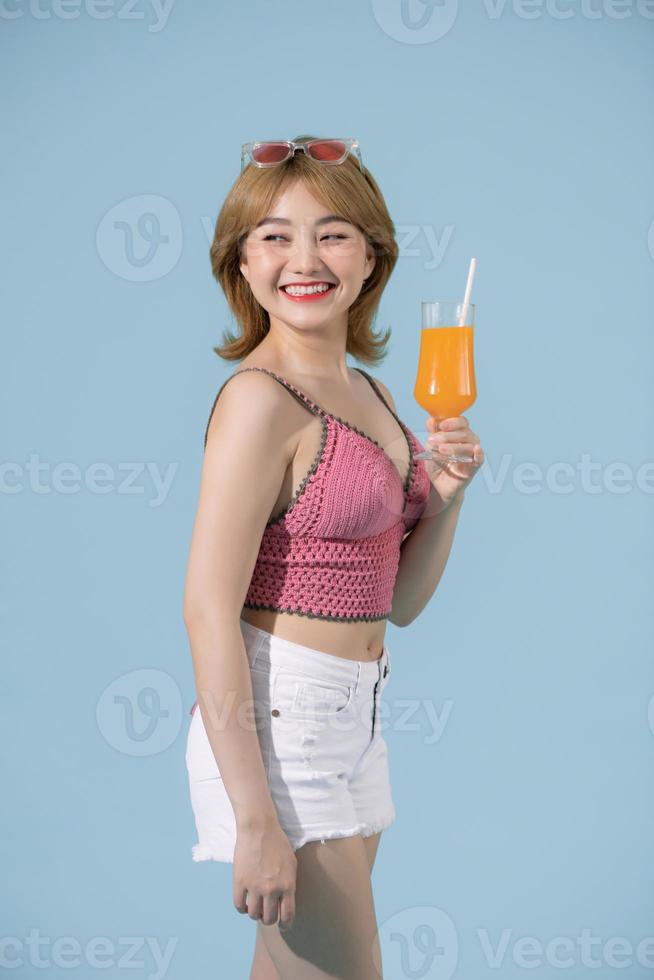 asiatisches Mädchen hält ein Glas Orangensaft in ihren Armen und lächelt, während sie im Studio posiert foto