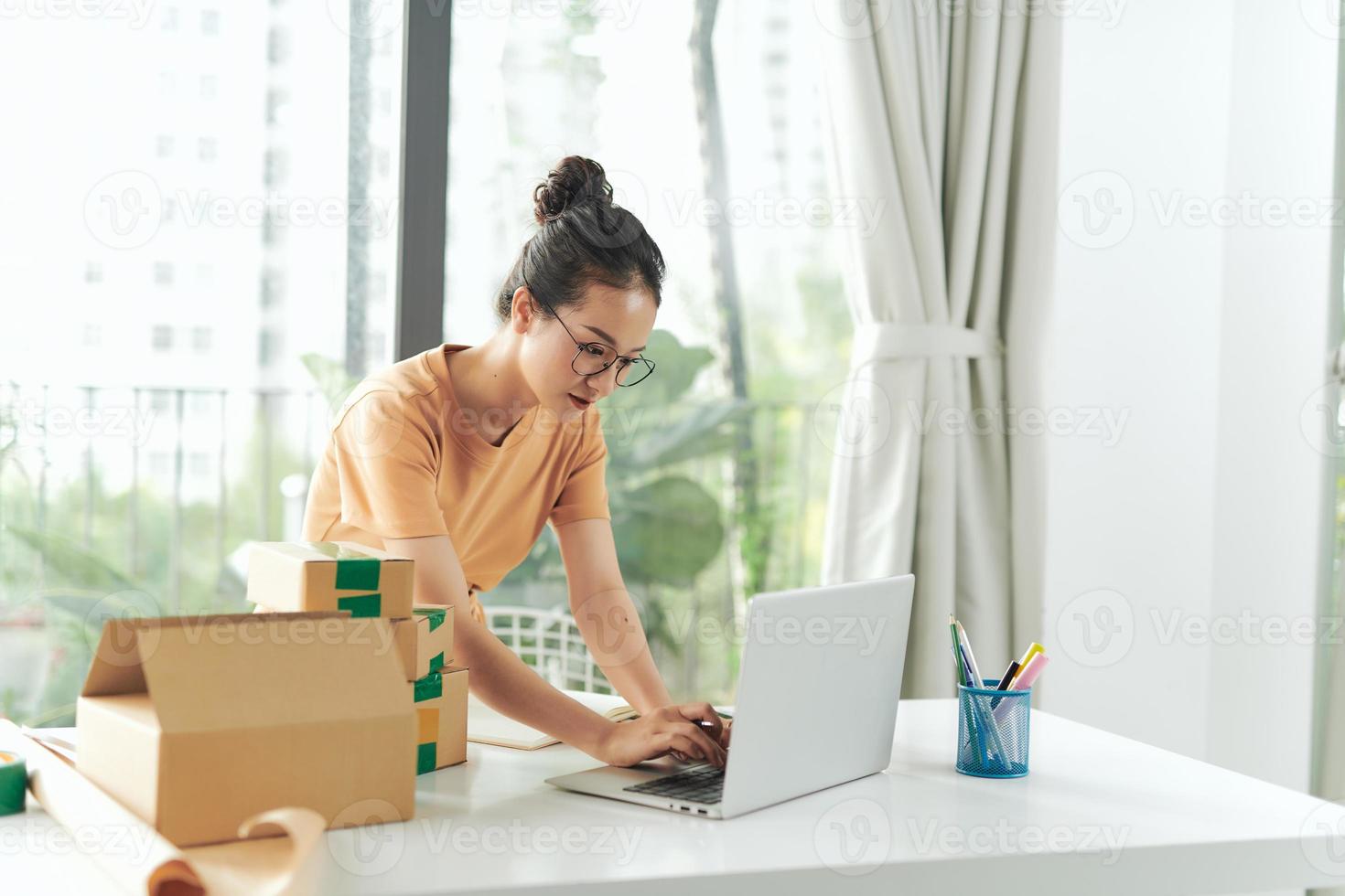 E-Commerce-Geschäftsmann arbeitet an einem Laptop und bereitet ihn für die Lieferung im Büro vor. foto