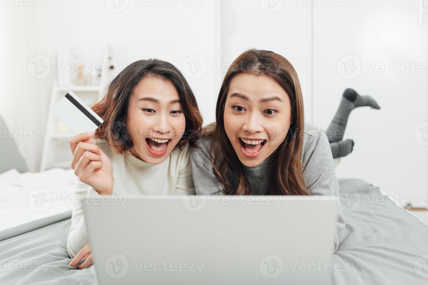 asiatische freundinnen sitzen im wohnzimmer mit digitalem tablet für online-einkäufe mit kreditkarte zusammen foto