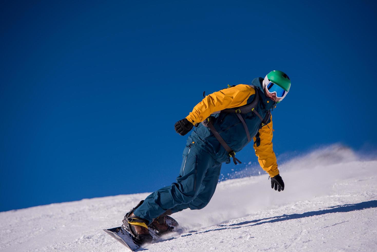 Snowboarder läuft die Piste hinunter und fährt im freien Stil foto