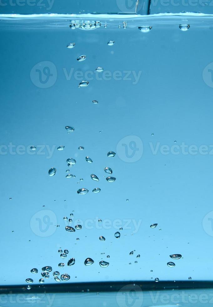 abstraktes Hintergrundbild von Blasen im Wasser. sauberes wasser mit wassertropfen und wellen. frisches wasser ein glas mit blasen blauem hintergrund. foto