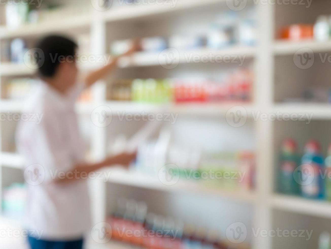 Verschwommener Apotheker, der Medikamente aus dem Regal in der Apotheke nimmt foto