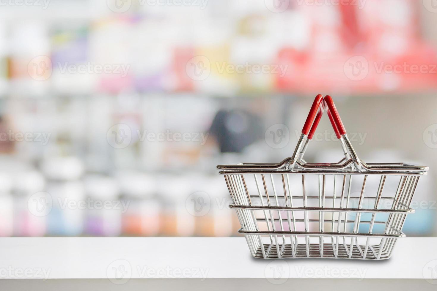 leerer einkaufskorb auf der apotheke drogerietheke mit unscharfen regalen mit medizin- und vitaminergänzungshintergrund foto