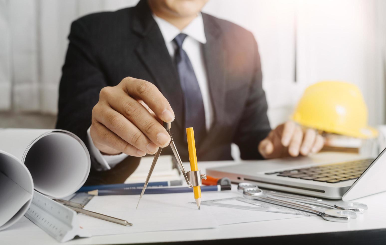 Zwei Kollegen diskutieren über Datenverarbeitung und Tablet, Laptop mit einem Architekturprojekt auf der Baustelle am Schreibtisch im Büro foto