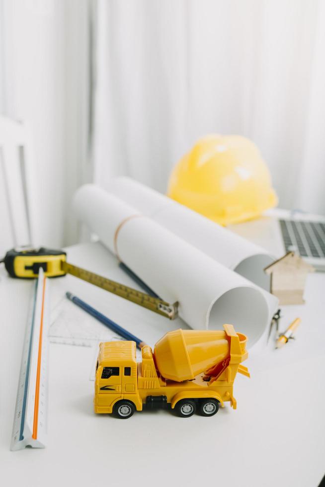 Zwei Kollegen diskutieren über Datenverarbeitung und Tablet, Laptop mit einem Architekturprojekt auf der Baustelle am Schreibtisch im Büro foto