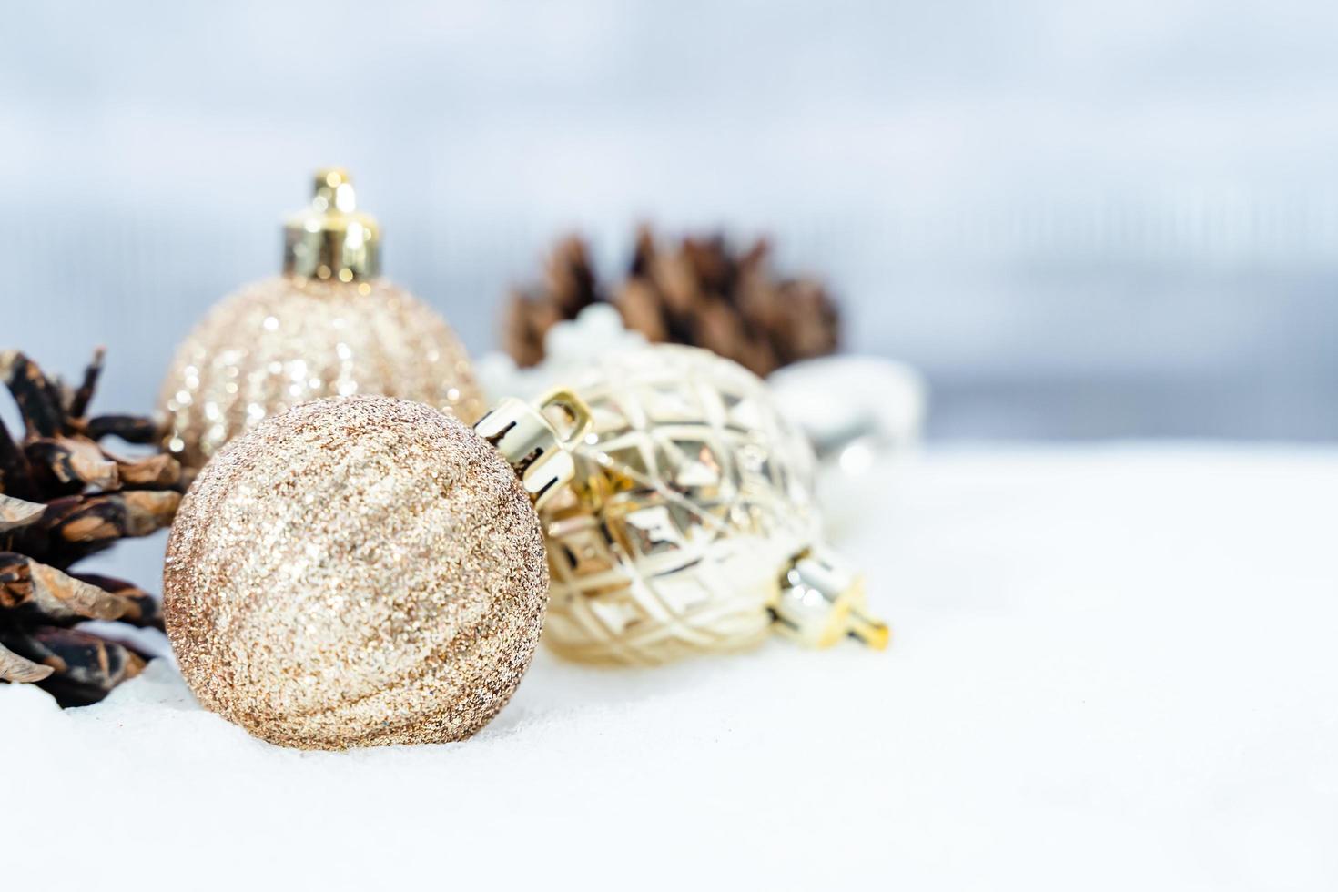 weihnachten des winters - weihnachtskugeln mit band auf schnee, winterferienkonzept. weihnachtsrote kugeln, goldene kugeln, kiefern- und schneeflockendekorationen im schneehintergrund foto