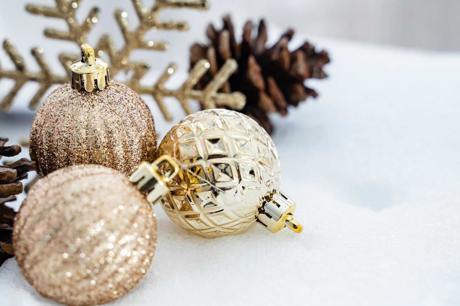 weihnachten des winters - weihnachtskugeln mit band auf schnee, winterferienkonzept. weihnachtsrote kugeln, goldene kugeln, kiefern- und schneeflockendekorationen im schneehintergrund foto