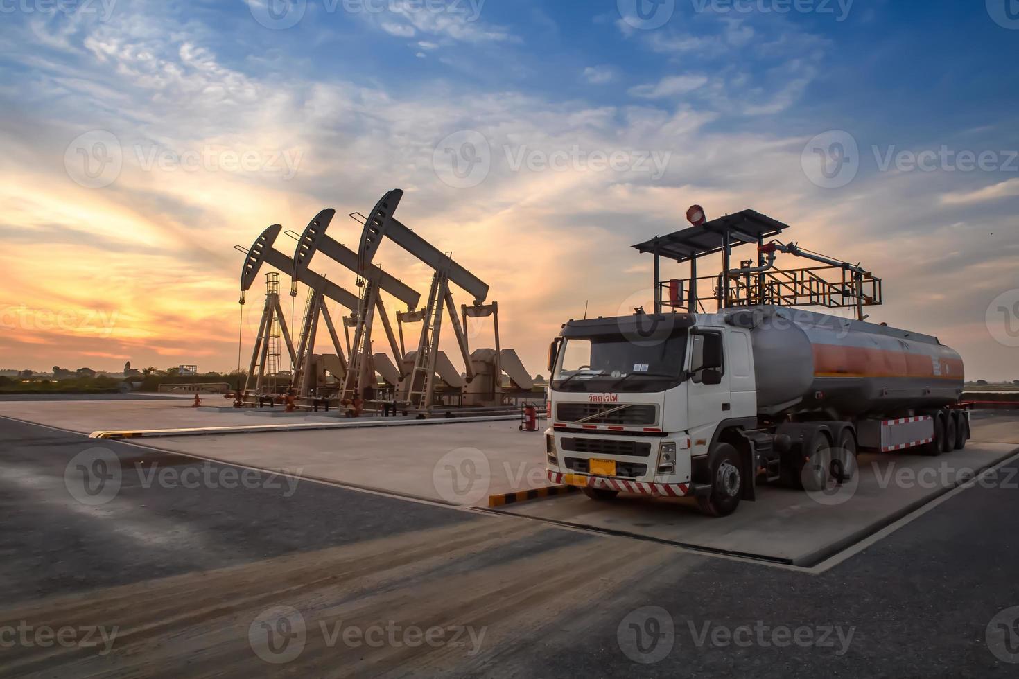 Bohrinseln und Öllastwagen arbeiten oder parken, um Öl in Ölfeldern abzulassen. bei Sonnenuntergang oder Sonnenaufgang am Abend oder am Morgen foto