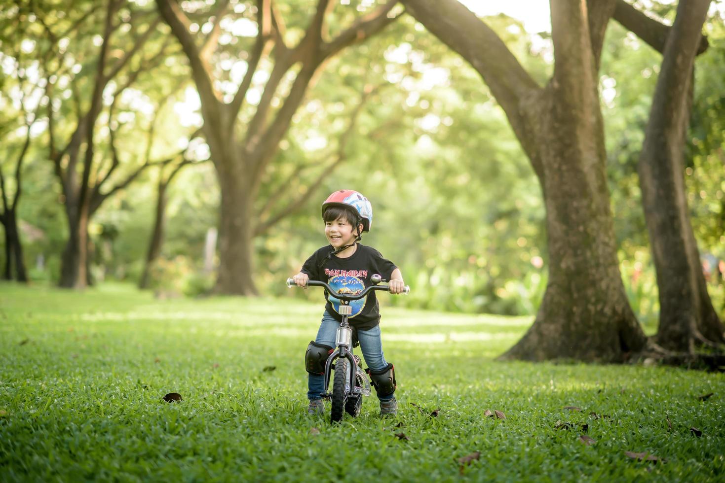 bangkok thailand - oktober 09, 2016 glücklicher fröhlicher kindjunge, der fahrrad im park in der natur fährt foto