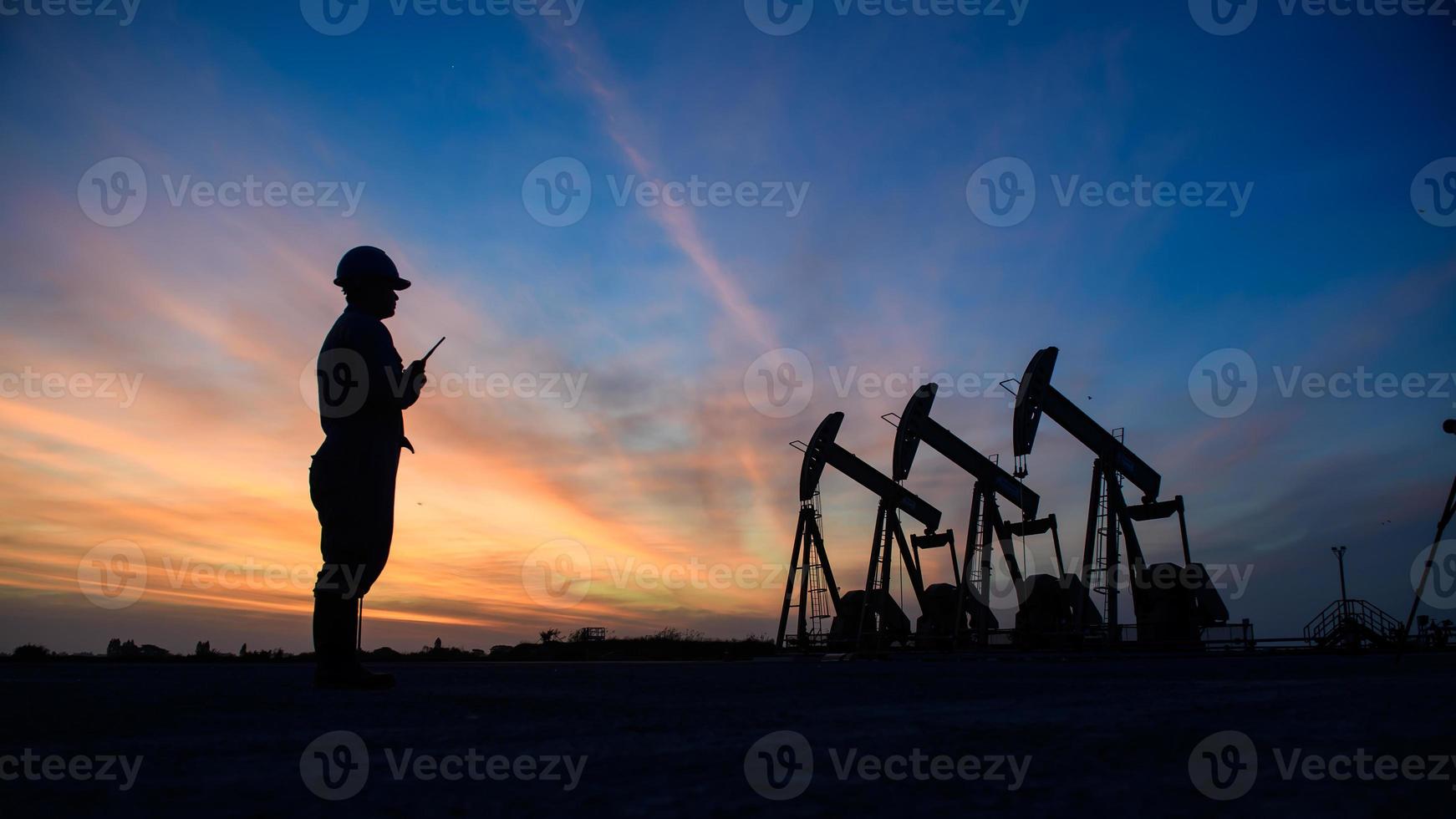 Silhouette von Ölarbeitern, die abends arbeiten, und schöner Sonnenuntergang. foto