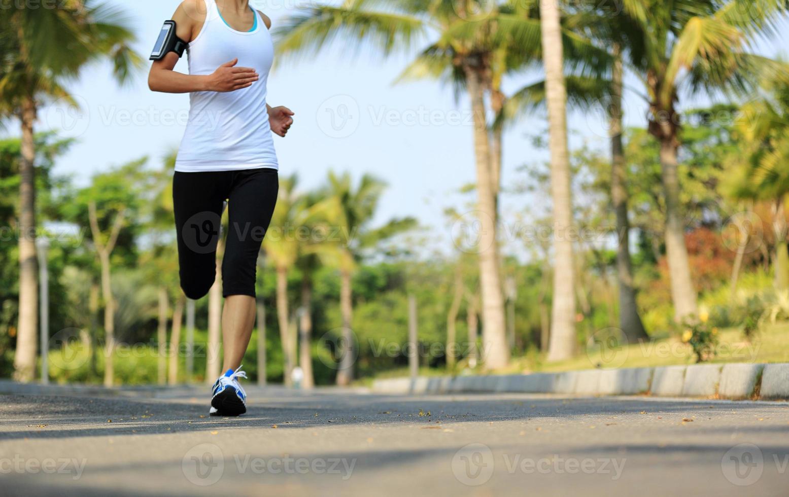 Läuferin, die auf tropischem Parkweg läuft foto