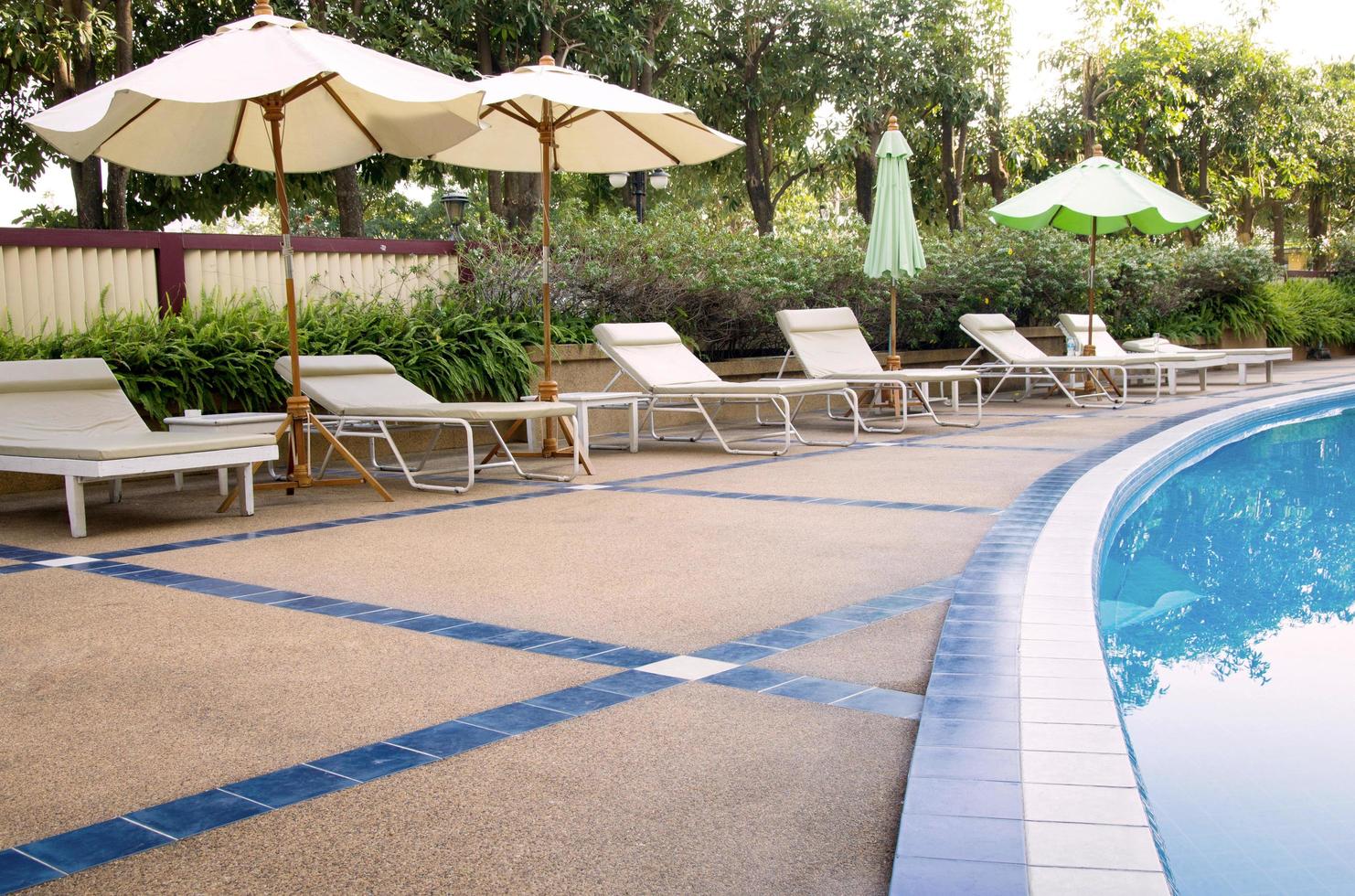 Liegestühle und Sonnenschirm am Swimmingpool foto