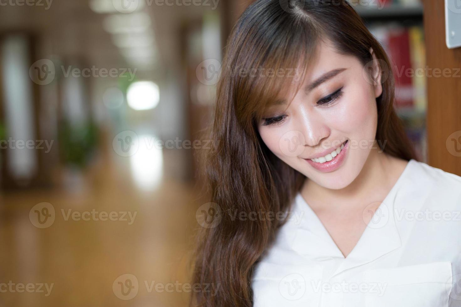 schöne asiatische Studentin Lesebuch in der Bibliothek foto