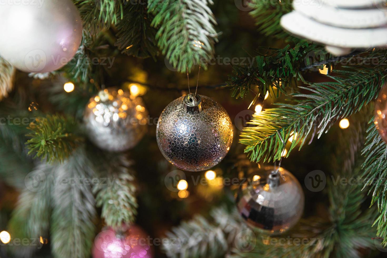 klassisches weihnachtsneujahr geschmückter neujahrsbaum mit silbernen ornamentdekorationen spielzeug und ball und defokussierten girlandenlichtern. modernes klassisches Urlaubsdesign. Heiligabend zu Hause. foto