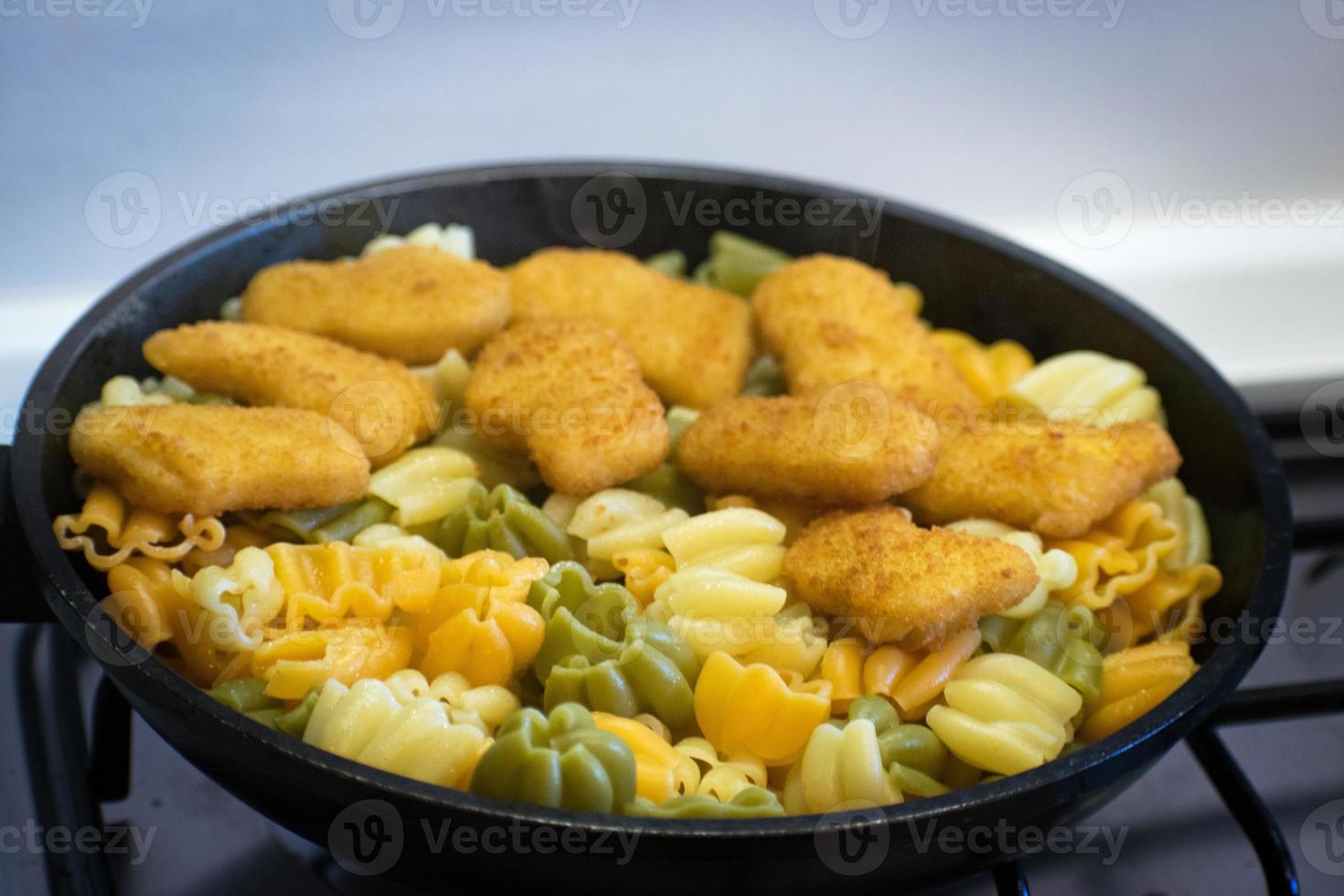 Nudeln mit Chicken Nuggets in einer Bratpfanne. frittierte Chicken Nuggets. leckere, knusprige Chicken Nuggets. Kindermenü. foto