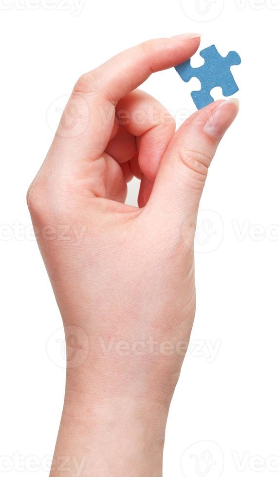 weibliche hand, die blaues puzzleteil hält foto