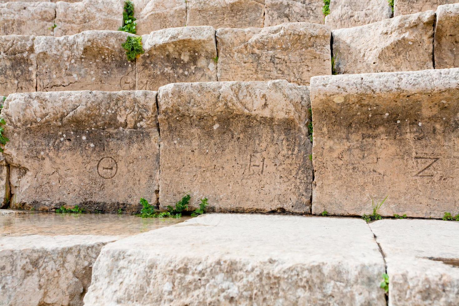 antike griechische zahlen auf steinsitzen im antiken großen südtheater, jerash foto