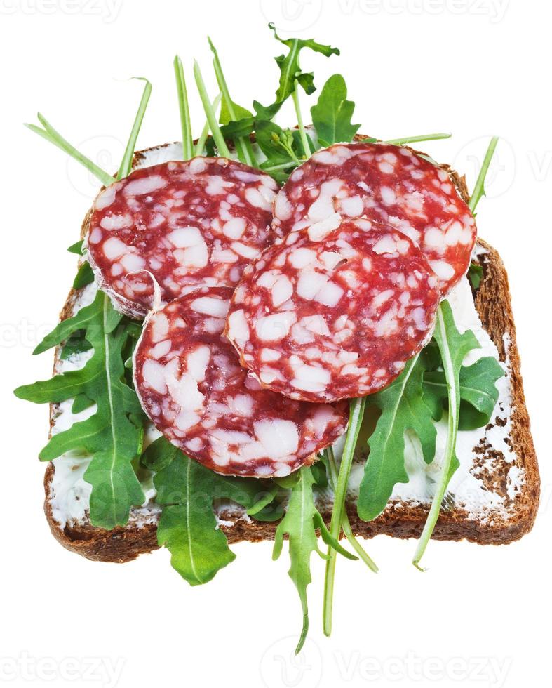 Sandwich aus Schwarzbrot, Salami und grünem Salat foto