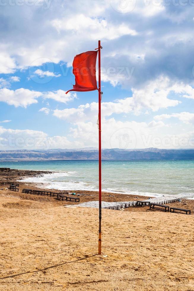 Rote Fahne am Strand des Toten Meeres im sonnigen Wintertag foto