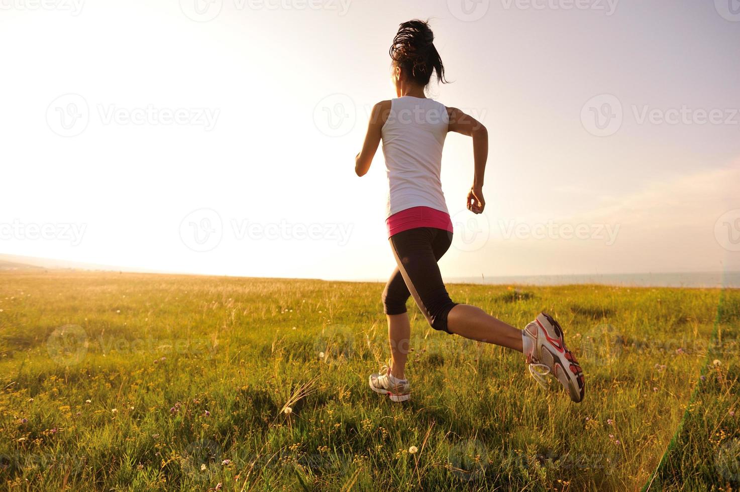 Läufer Athlet läuft auf Sonnenaufgang / Sonnenuntergang Grasfeld foto