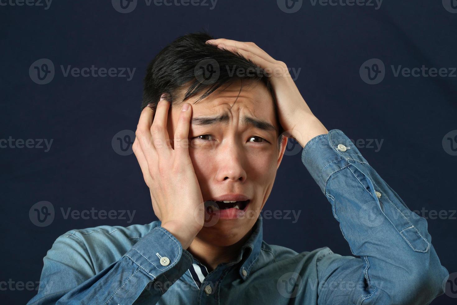 enttäuschter junger asiatischer Mann, der weint und seitwärts schaut foto