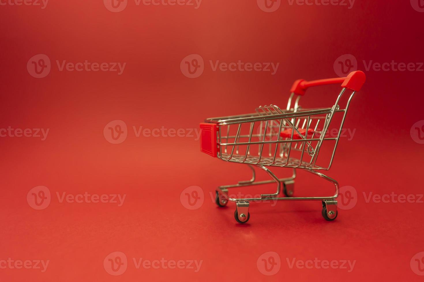 ein Einkaufswagen, der auf einem roten Hintergrund steht foto