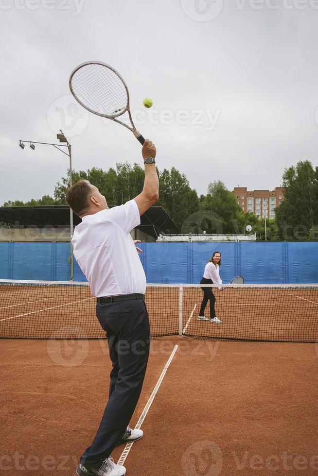Frischvermählte spielen Tennis auf dem Platz, der die Familienbeziehungen symbolisiert foto