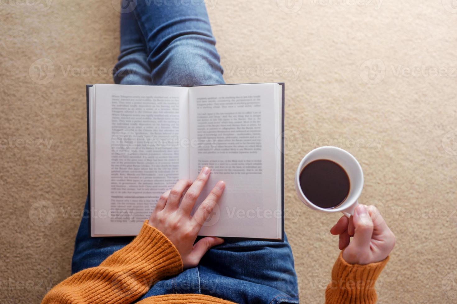 Lesekonzept. weicher fokus der jungen frau, die sich bei buch und kaffee in einem gemütlichen haus entspannt, auf dem boden sitzt, draufsicht foto