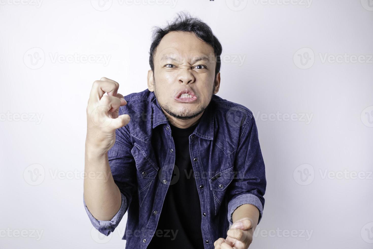 ein unzufriedener junger asiatischer mann sieht verärgert aus und trägt ein blaues marinehemd mit gereizten gesichtsausdrücken foto