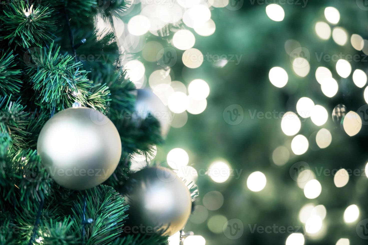 Nahaufnahme einer roten Kugel, die an einem geschmückten Weihnachtsbaum hängt, auf verschwommenen Lichtern mit geschmücktem Baum, funkelnden und bokeh Hintergrund. Kopieren Sie Platz für Ihren Text. foto