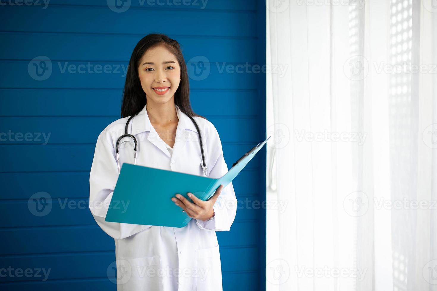 schöner asiatischer arzt mit stethoskop und dokumentordner, gesundheits- und medizinkonzept. foto