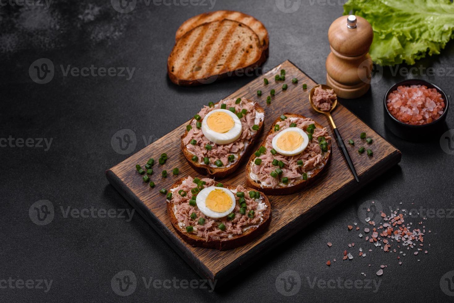 leckeres gesundes Sandwich mit Thunfisch, Croutons, gekochtem Ei, Kräutern und Butter foto