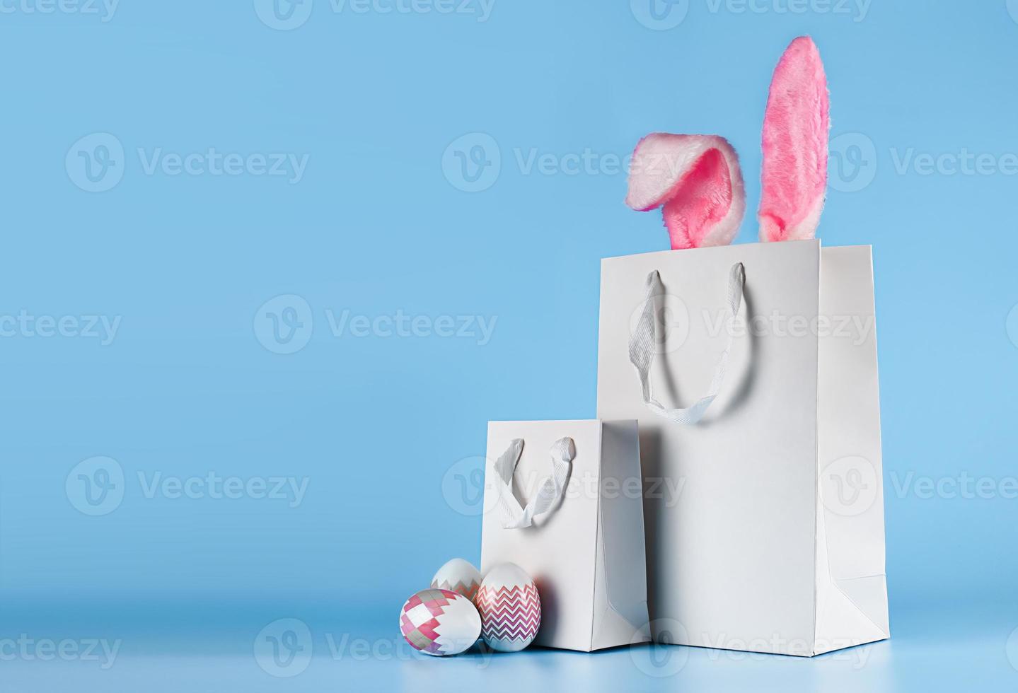 Banner auf blauem Hintergrund. das konzept des online-shoppings für ostern, einkäufe und verkauf für den urlaub. Geschenktüte mit Hasenohren und Ostereiern foto