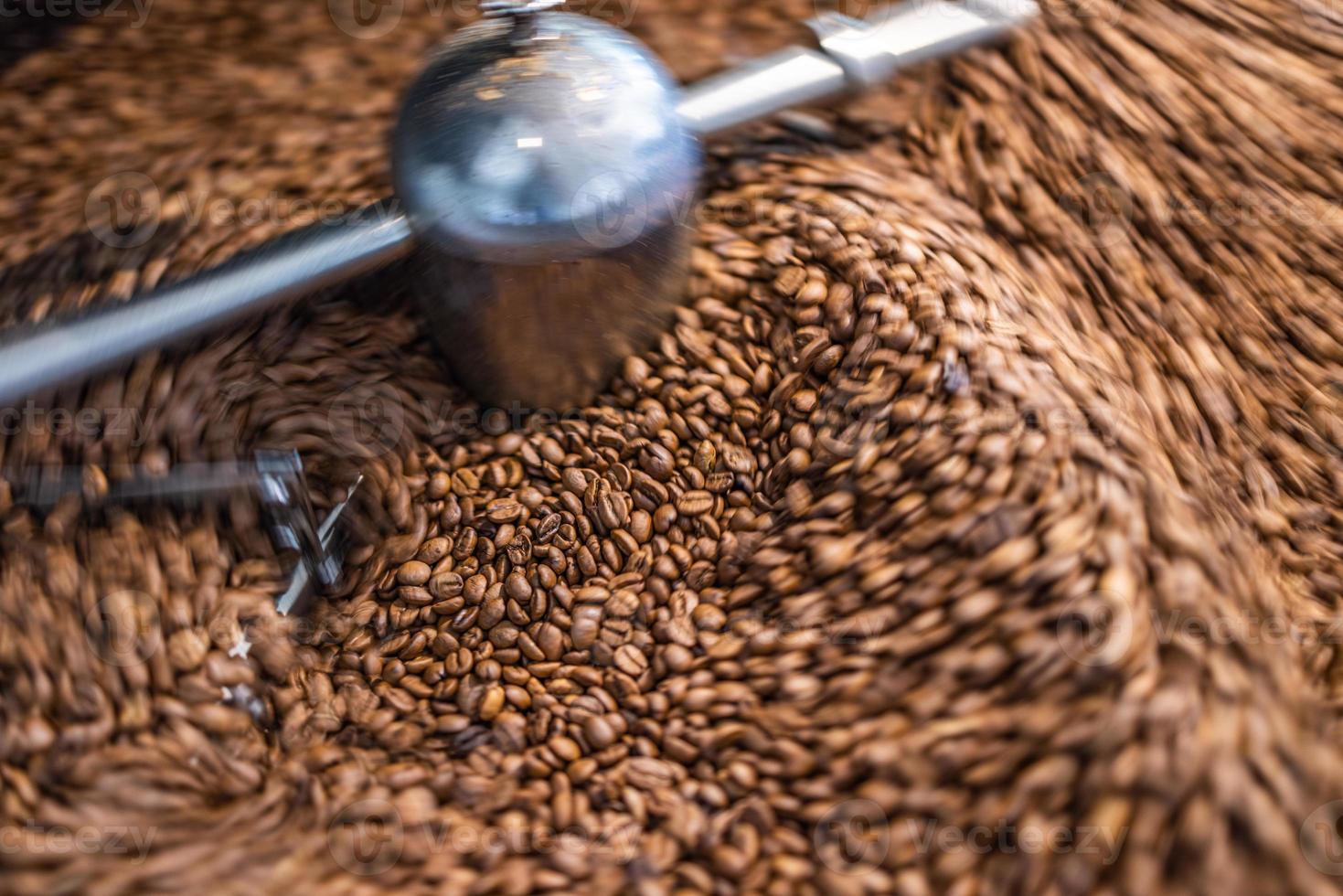 bester Kaffeehintergrund. frisch geröstete Kaffeebohnen in Bewegung. künstlerisches Heißgetränke-Nahaufnahmekonzept. Kaffeerösterzylinder, der Kaffeebohnen röstet und mischt foto