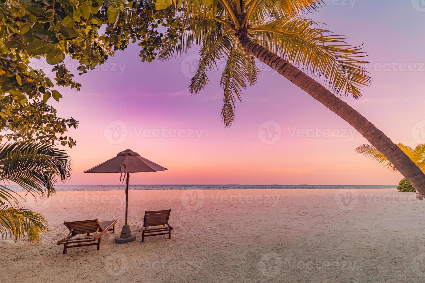 perfekte tropische Sonnenuntergangslandschaft, zwei Sonnenliegen, Liegestühle, Sonnenschirm unter Palmen. weißer Sand, Meerblick mit Horizont, bunter Dämmerungshimmel, Ruhe und Entspannung. inspirierendes Strandresort-Hotel foto