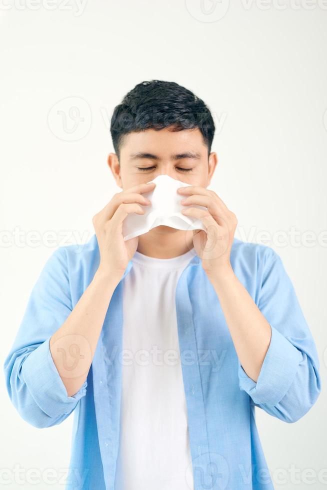 kalter junger mann niest in eine serviette foto