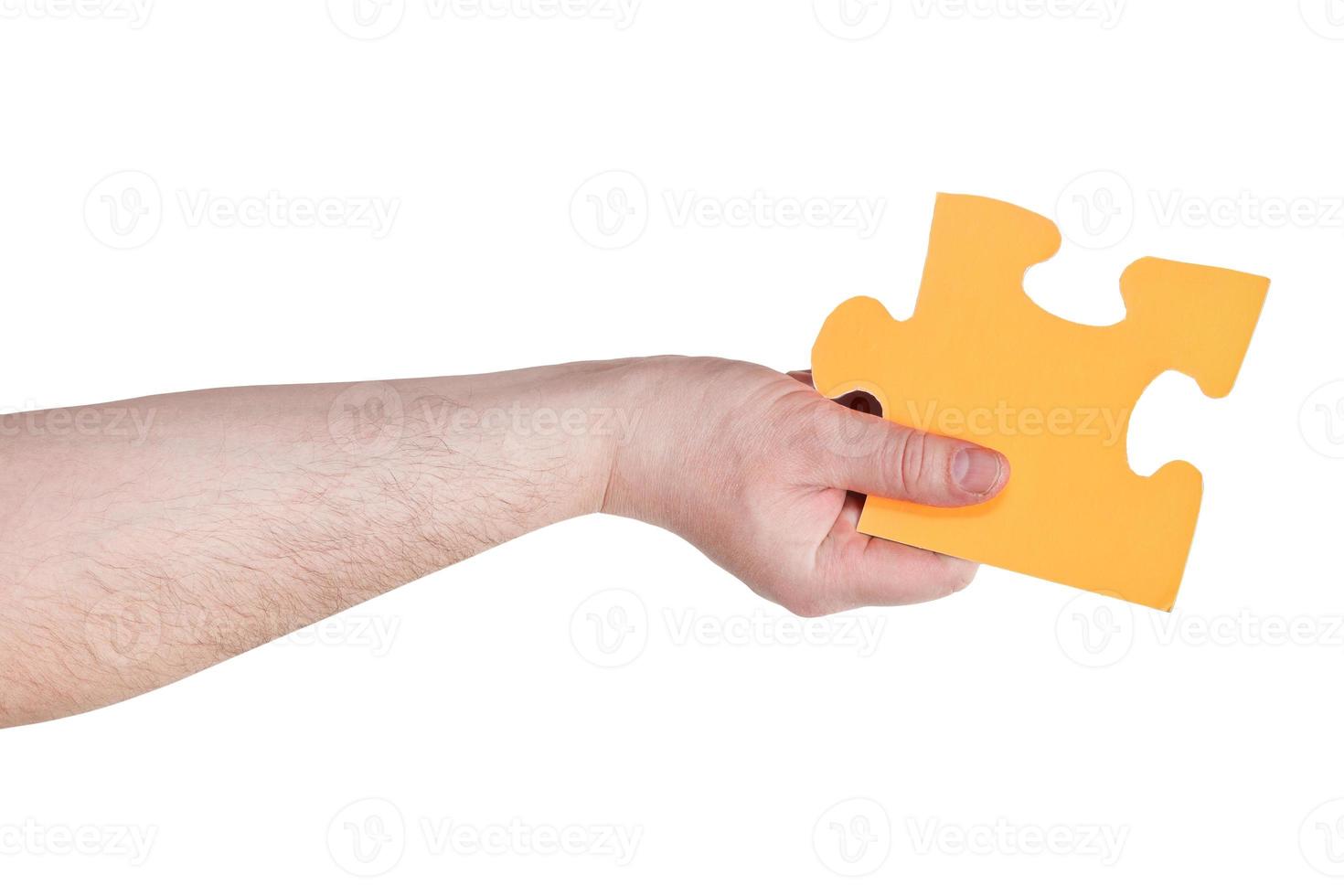 männliche hand, die großes gelbes papierpuzzleteil hält foto
