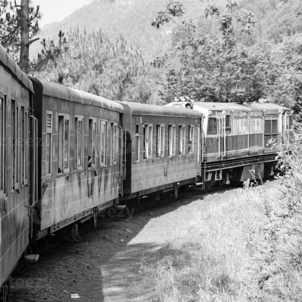 spielzeugeisenbahn, die sich am berghang bewegt, schöne aussicht, eine seite des berges, eine seite des tals, die auf der eisenbahn zum hügel fährt, inmitten grüner naturwälder. spielzeugeisenbahn von kalka nach shimla in indien-schwarz und weiß foto