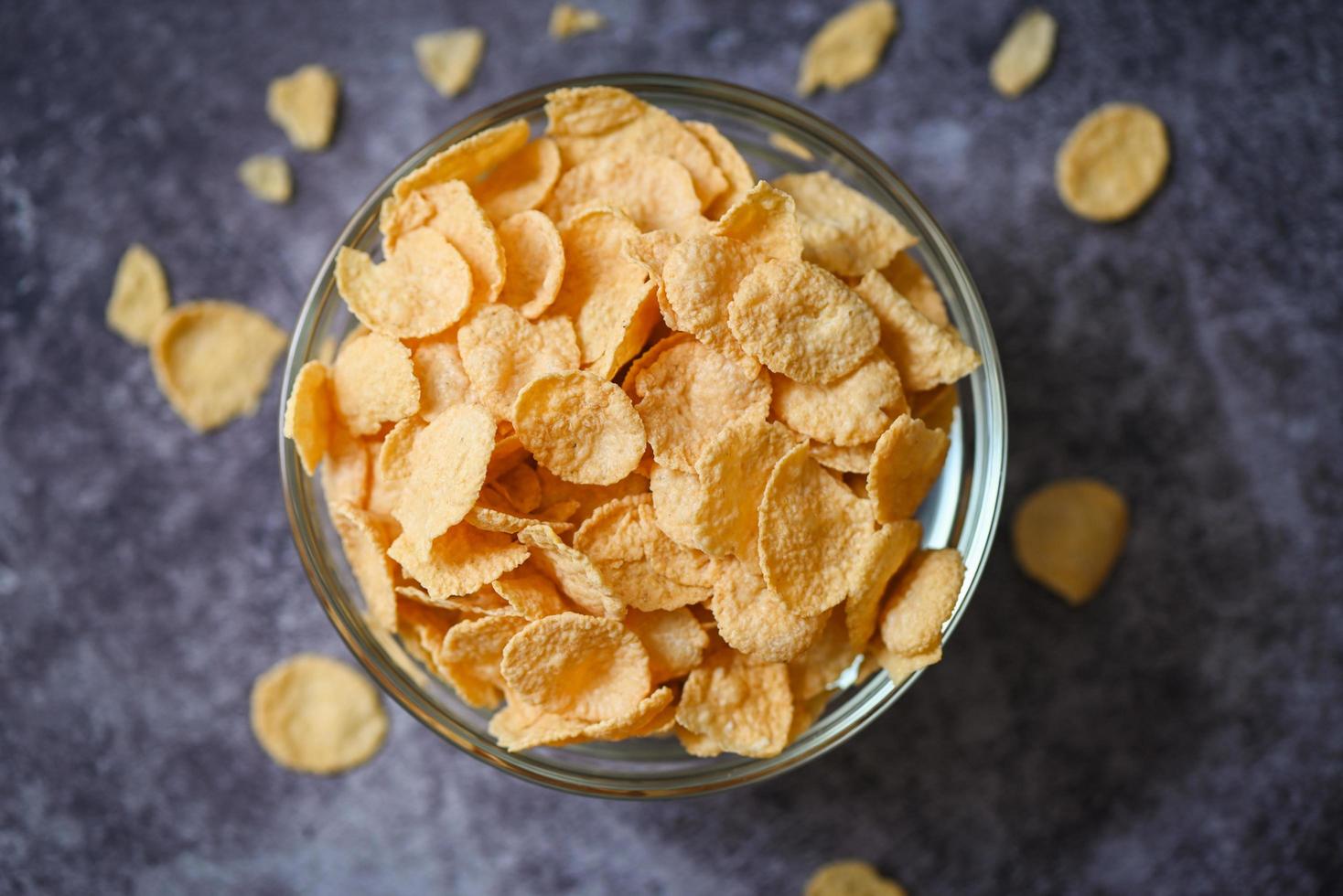 cornflakes schüssel frühstücksnahrung und snack für gesundes lebensmittelkonzept, morgenfrühstück frisches vollkornmüsli, cornflakes auf dunklem hintergrund foto