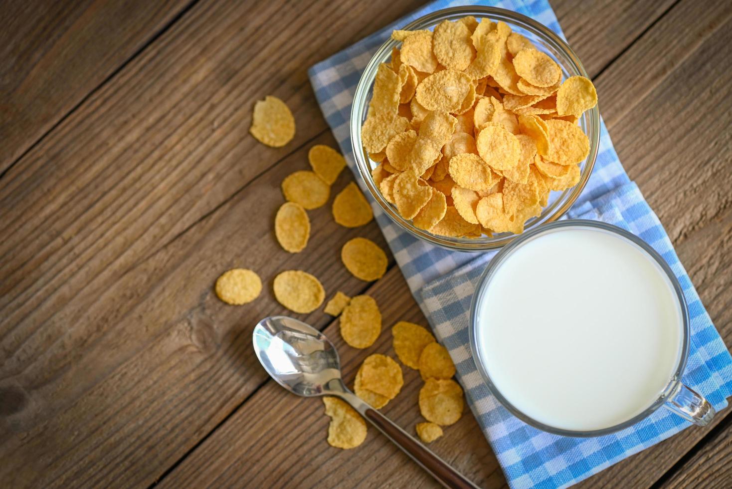 cornflakes schüssel frühstücksnahrung und snack für gesundes lebensmittelkonzept, morgenfrühstück frisches vollkorngetreide, cornflakes mit milch auf hölzernem hintergrund foto