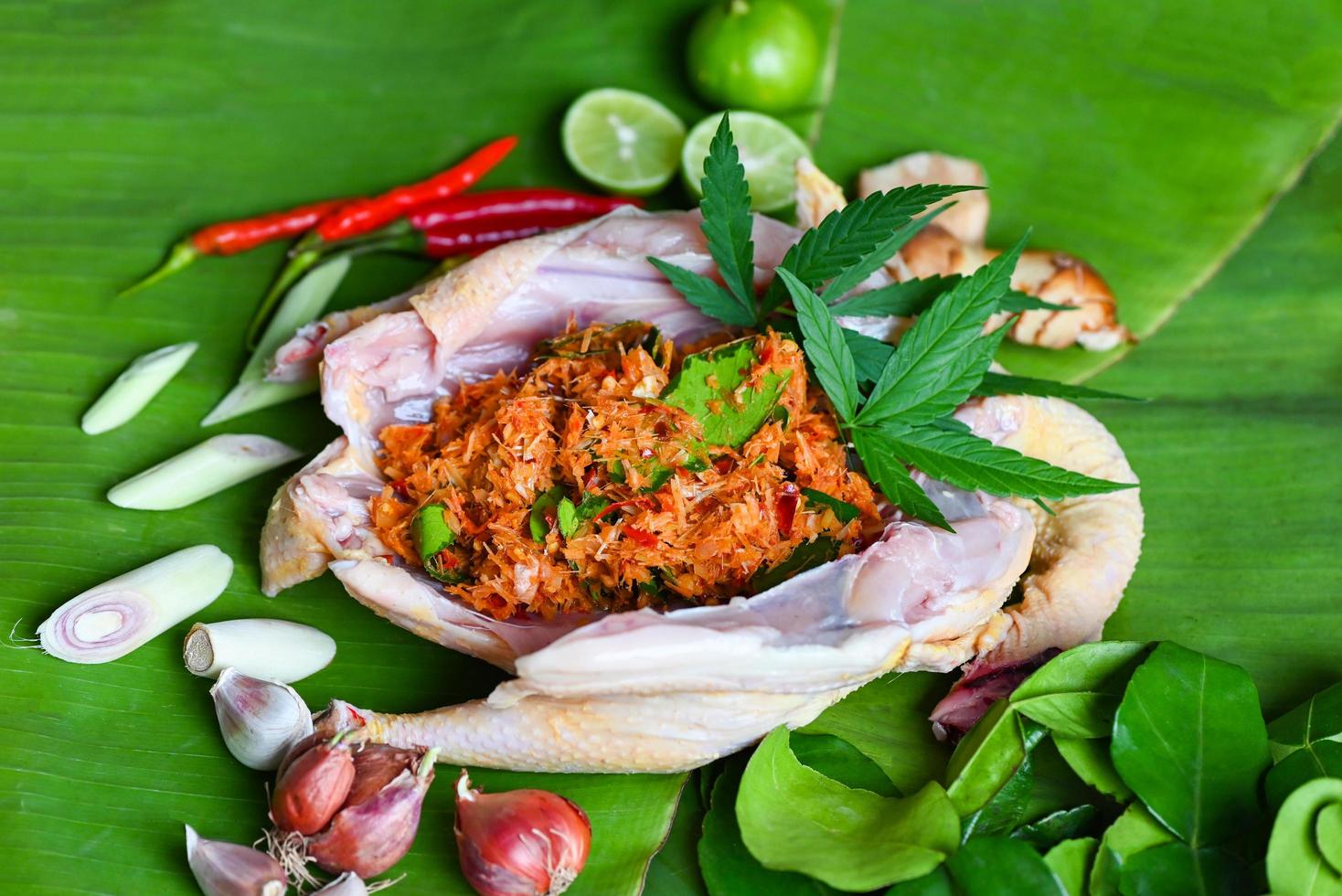 Cannabis-Lebensmittel zum Kochen mit frischem Hähnchen-Cannabisblatt, Marihuana-Gemüse, Kräutern und Gewürzen, Zutaten auf Bananenblatthintergrund, rohe Hühnchen-Hanfblattpflanze mit cbd-Kräutern - thailändisches Essen foto