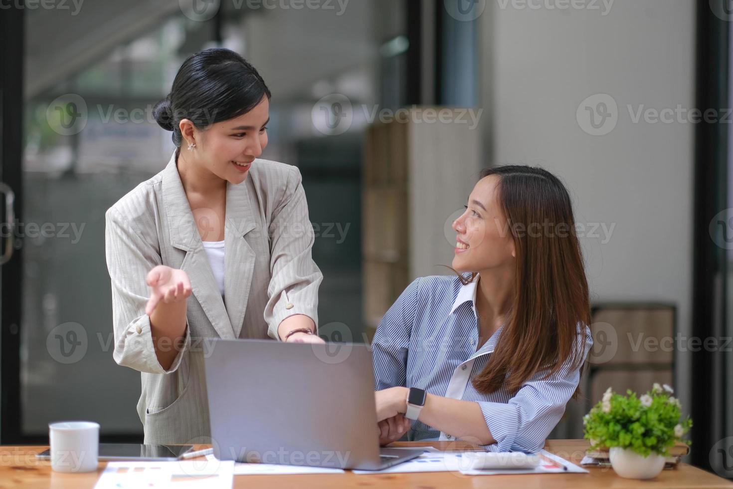 zwei junge asiatische geschäftsfrauen diskutieren mit der ideenpräsentation eines neuen startup-projekts, analysieren planungs- und finanzstatistiken sowie den investitionsmarkt im büro. foto